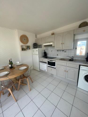 - une cuisine avec des placards blancs, une table, une table et des chaises dans l'établissement Évasion Méditerranéenne, à Gruissan