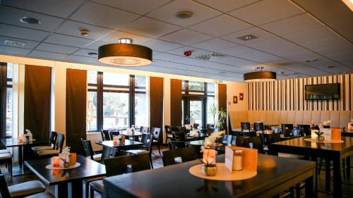 a dining room with tables and chairs and windows at Parkhotel Olsberg in Olsberg