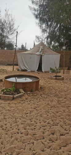 a tub in the sand with a tent in the background at Les jardins fleuris de lompoul sur mer in Tioukougne Peul
