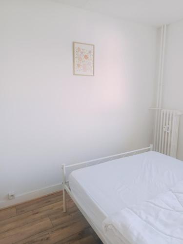 - un lit blanc dans une chambre avec une photo sur le mur dans l'établissement Chambre lumineuse et cosy proche des transports et commerces, à Besançon