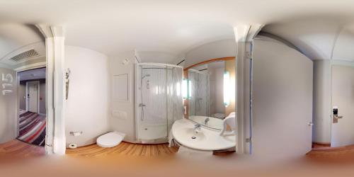 a bathroom with a tub and a sink and a mirror at ibis Dinant Centre in Dinant