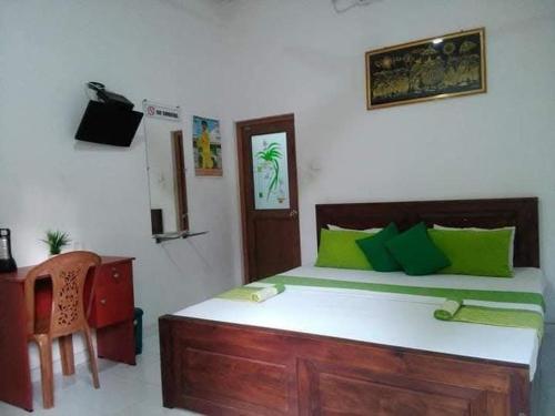 a bedroom with a bed with green pillows and a desk at Dinimuthu Rest Inn in Wellawaya