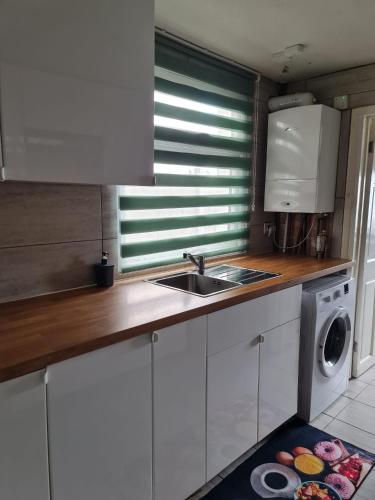a kitchen with a sink and a washing machine at The Oaks in Grays Thurrock