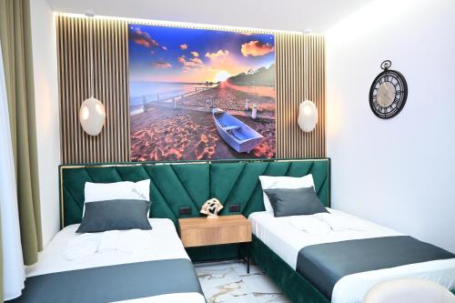 two beds in a room with a beach and a painting at Vila La Familia in Ksamil