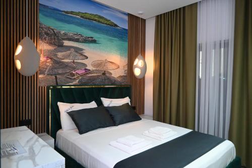 a bedroom with a bed with a painting on the wall at Vila La Familia in Ksamil