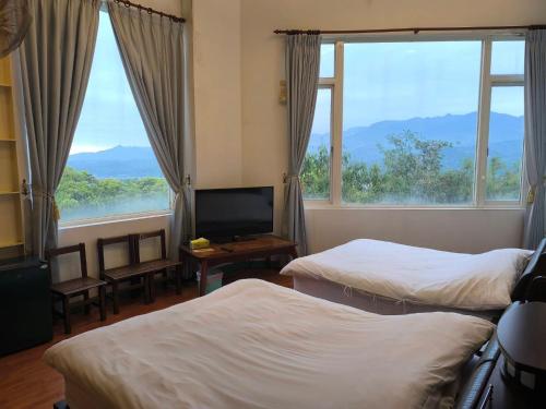 a hotel room with two beds and a television at 馨舍民宿 in Xinshe