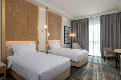 a hotel room with two beds and a desk at Slemani Rotana in As Sulaymānīyah