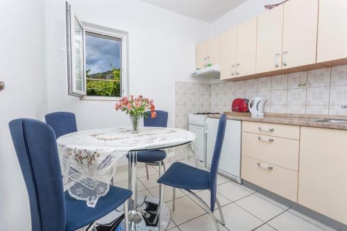a kitchen with a table with blue chairs and a vase of flowers at Apartman Ana in Hvar