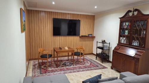 a living room with a table and a television on a wall at Theo's City House in Funchal