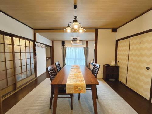 a dining room with a wooden table and chairs at 民宿ひだまり Minsyuku Hidamari in Kurashiki