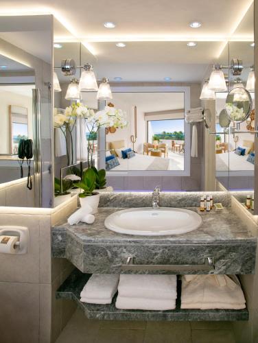 a bathroom with a sink and a large mirror at Azia Resort & Spa in Paphos City