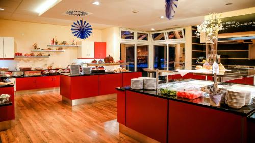 a large kitchen with red cabinets and counters at Parkhotel Olsberg in Olsberg