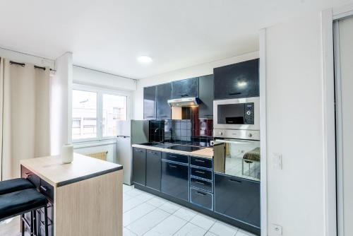 une cuisine avec des armoires noires et un four à plaques de cuisson dans l'établissement M70 Marquer Studio proche de la gare, à Annemasse