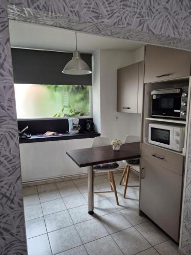 une petite cuisine avec une table et un micro-ondes dans l'établissement 1 rue des romains studio meublé clauss, à Niederbronn-les-Bains