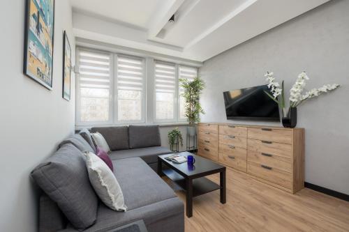 a living room with a couch and a tv at Stylowe Apartamenty w Centrum Gdyni i Blisko Plaży by Noclegi Renters in Gdynia
