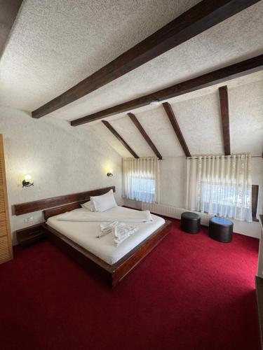 a bedroom with a large bed with a red carpet at House Of River in Moieciu de Sus