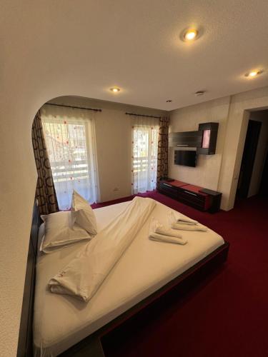 a bedroom with a large bed with white sheets at House Of River in Moieciu de Sus