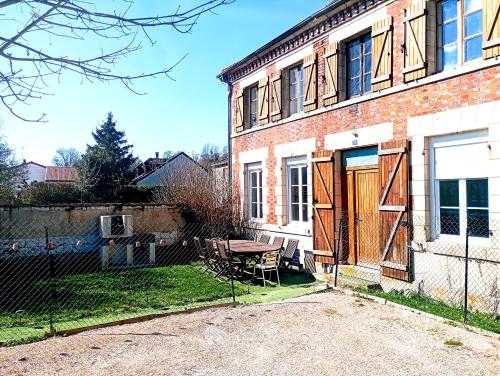 a house with a fence and a table in front of it at Magnifique bâtisse champenoise, jardins, billards, parking in Écury-sur-Coole