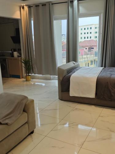 a bedroom with a bed and a couch and a window at Tizora Mini in Accra