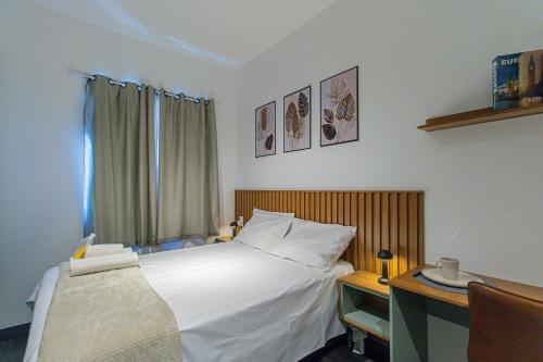 a bedroom with a large white bed and a desk at Aconchegante Studio em Sao Paulo - SP-A713 in São Caetano do Sul