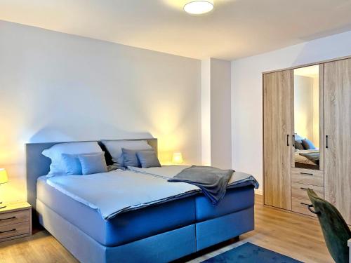 une chambre avec un lit bleu et un miroir dans l'établissement YiPY Apartments am Landesmuseum Halle, à Halle-sur-Saale