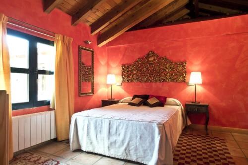 a red bedroom with a bed and two lamps at Hotel Sara De Ur in La Cabrera
