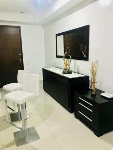 Sala de estar blanca con silla blanca y espejo en Aparta estudio Bucaramanga, en Bucaramanga