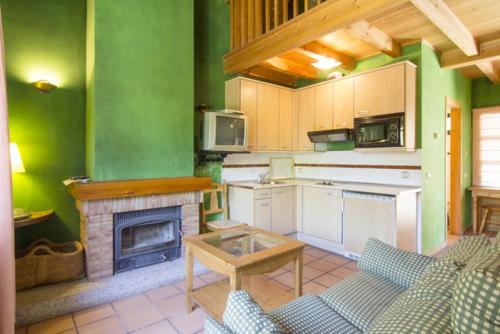 a large kitchen with green walls and a fireplace at Hotel Sara De Ur in La Cabrera