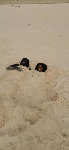 two people are buried in the sand at Les jardins fleuris de lompoul sur mer in Tioukougne Peul