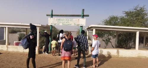 a group of people standing at a bus stop at Les jardins fleuris de lompoul sur mer in Tioukougne Peul