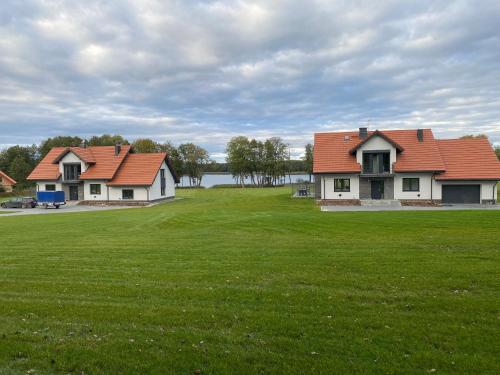two houses with red roofs on a green field at Osada Limajno Dom Żurawia in Cerkiewnik