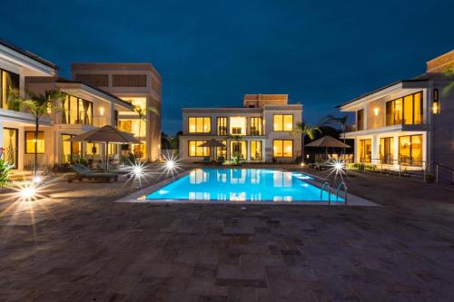 a swimming pool in front of a building at night at Amkia Villas Diani in Diani Beach
