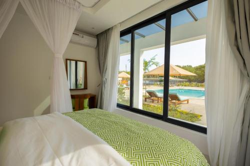 a bedroom with a bed and a view of a pool at Amkia Villas Diani in Diani Beach