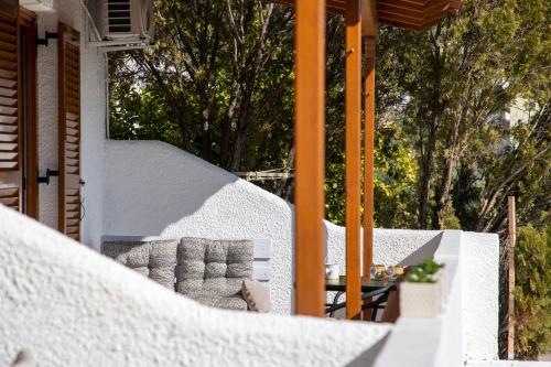 a white house with a chair on a porch at Zefi's Aegina Apartment in Kapótidhes