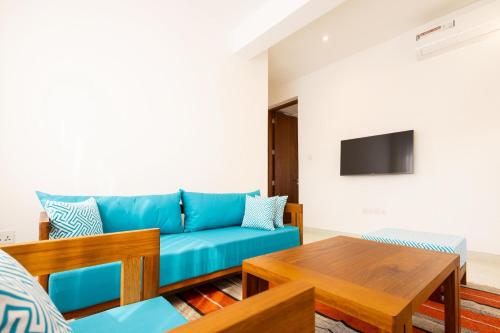 a living room with a blue couch and a table at Amkia Villas Diani in Diani Beach