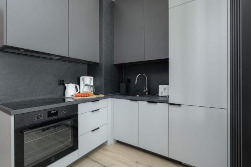 a kitchen with white cabinets and black appliances at Baltic Waves Resort w Międzyzdrojach Blisko Plaży & Parking by Noclegi Renters in Międzyzdroje