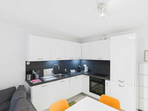 a white kitchen with white cabinets and orange chairs at Court House Sonvico in Lugano