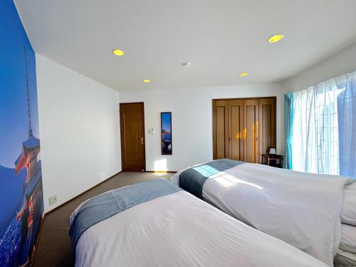 a bedroom with two beds and a large window at Ango Yamanakako2 in Oyama