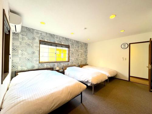 a bedroom with two beds and a window at Ango Yamanakako2 in Oyama