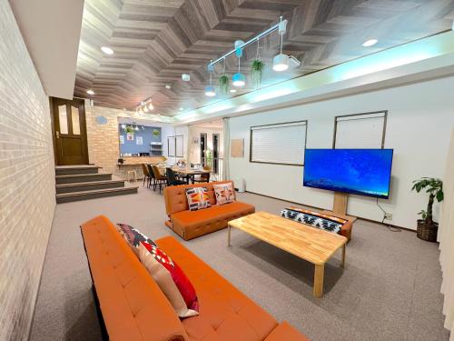 a living room with orange furniture and a flat screen tv at Ango Yamanakako2 in Oyama