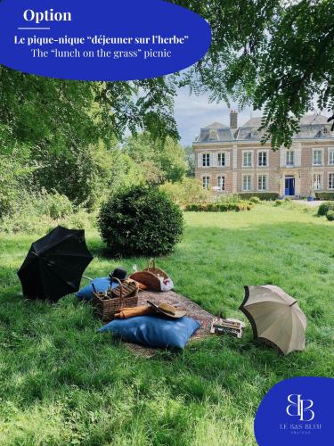 a picnic in the grass in front of a building at L'Indépendance - Cottage - Château Le Bas Bleu in Quesnoy-le-Montant