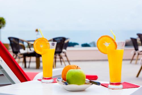 three glasses of orange juice and a bowl of fruit on a table at Guest House Pasha in Ulcinj