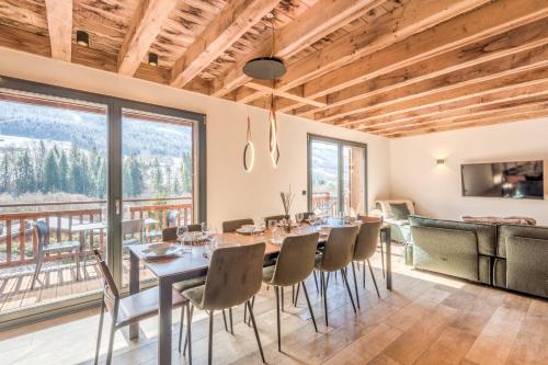 une salle à manger avec une table, des chaises et des fenêtres dans l'établissement Chalet Shana - Welkeys, à Praz-sur-Arly
