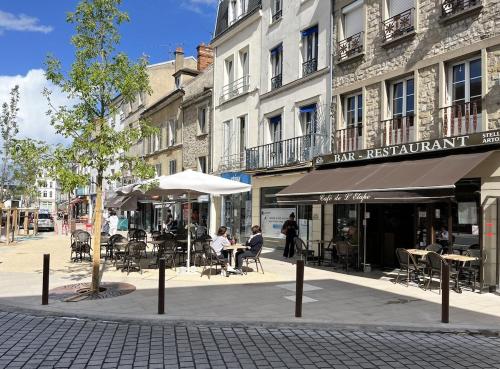 une rue avec des tables et des chaises devant un bâtiment dans l'établissement Duplex en centre-ville, à Fontainebleau