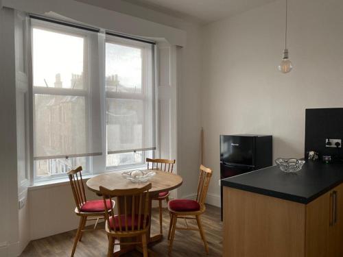 a kitchen with a table and chairs and a kitchen with a refrigerator at Spacious 3 bedroom apartment in Campbeltown centre in Campbeltown