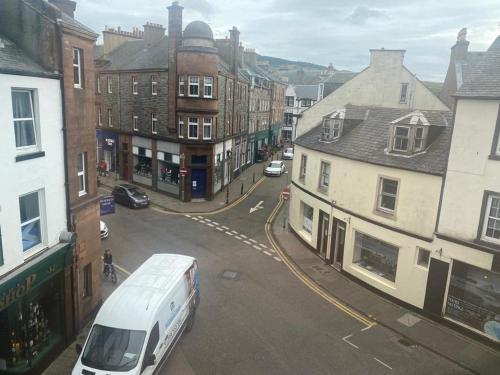 a white van driving down a city street with buildings at Spacious 3 bedroom apartment in Campbeltown centre in Campbeltown