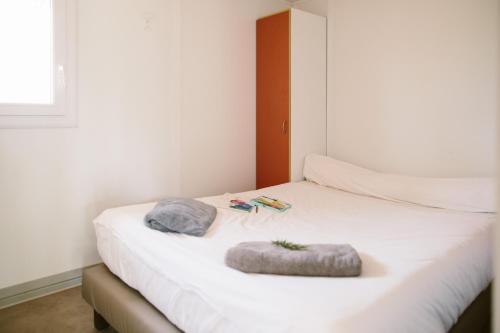 un lit blanc avec deux oreillers dessus dans l'établissement Camping Naturiste Riva Bella 4*, à Linguizzetta