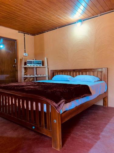 a bedroom with a wooden bed with blue pillows at Nomadcasa Rooms in Kanthalloor
