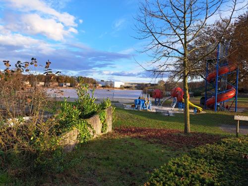 a park with a playground next to a body of water at Boshuisje op de Schatberg in Sevenum