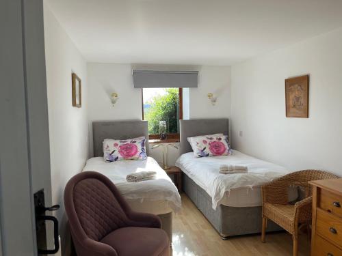 a room with two beds and a chair and a window at Cocklekitty Cottage in Kelso